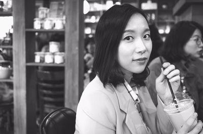 Portrait of woman holding disposable cup at restaurant