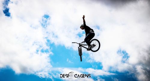 Low angle view of man riding bicycle against sky