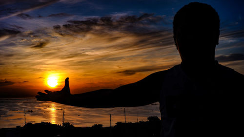 Rear view of silhouette man standing against sky during sunset