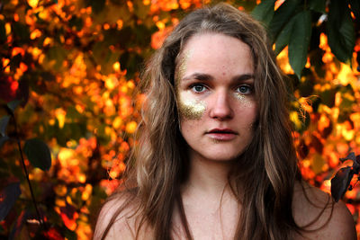 Close-up portrait of young woman with glitter make-up by trees