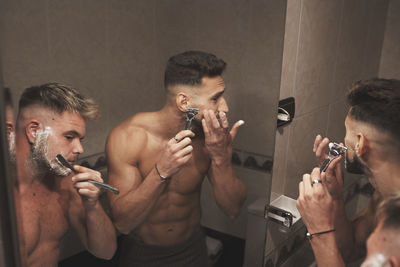 A couple of gay guys are shaving together in the bathroom at home