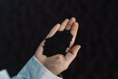 Cropped hand of woman holding paper against black background