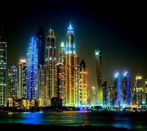 Illuminated modern buildings against sky at night