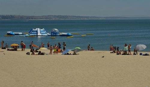 People enjoying on beach against clear sky