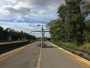 Railroad tracks by road against sky