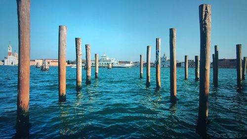 Wooden posts in sea against sky