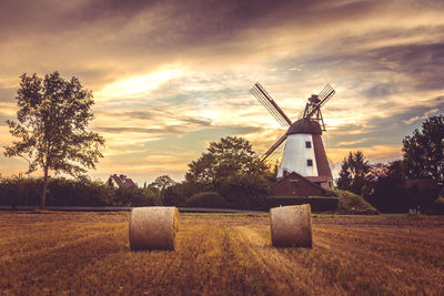 Traditional windmill on field against sky at sunset