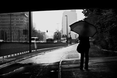 Rear view of man walking on road in rain