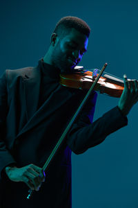 Midsection of man playing violin against clear sky