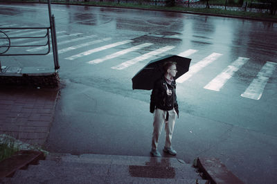 Full length of man standing on wet street during monsoon