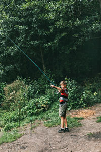 A teenage boy with a fishing rod is standing on a boat. a child catches fish alone 