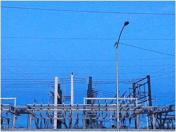 Low angle view of electricity pylon against blue sky