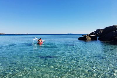 People kayak in sea against sky