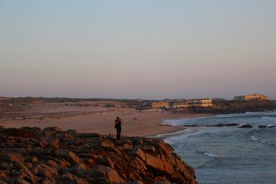 Man photographing while standing against sky during sunset