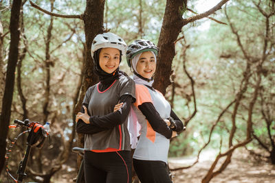 Portrait of young female friends standing against trees