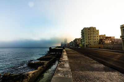 City buildings by sea against sky