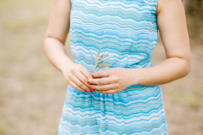 Midsection of woman holding plant while standing outdoors