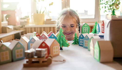 Origami advent calendar, paper craft. girl looking upon paper houses with number and paper tree