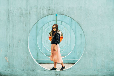 Full length of woman standing against wall