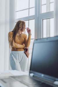 Woman looking through window at home