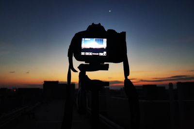 Silhouette of man photographing against sky during sunset