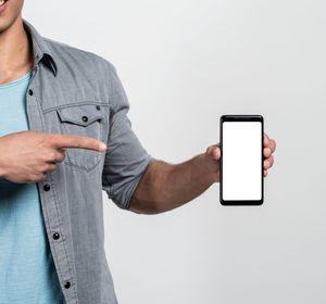 Midsection of man using smart phone against white background