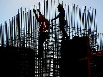 Low angle view of men working at construction site against sky