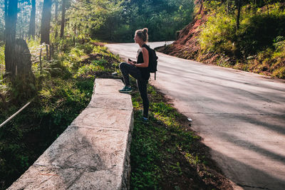 Woman sitting on footpath amidst plants