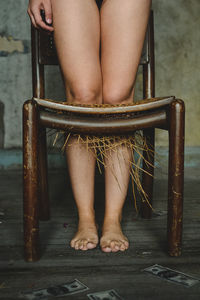 Low section of woman standing in broken chair