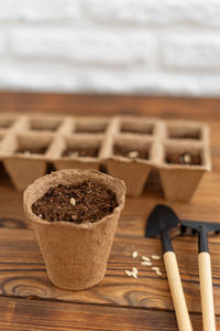 Planting seeds into peat pot on old grunge wooden table.  home gardening. top view. selective focus.