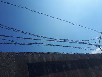 Low angle view of barbed wire against sky