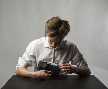 Man photographing while sitting on table