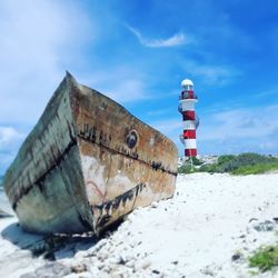 Lighthouse by sea against sky