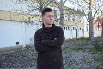 Portrait of young man standing by bare tree