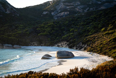 Rocks by sea against mountains