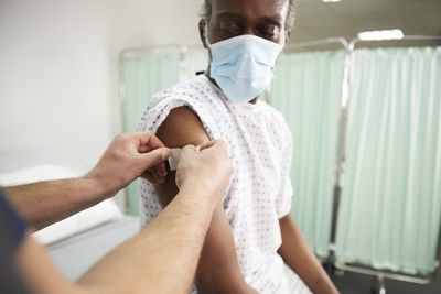 Nurse with adhesive bandage on patient's arm in medical room