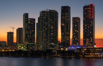 Illuminated buildings in city against sky