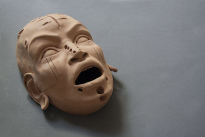 Sculpture of the face in clay. female mask with open mouth on a grey floor. dark and gothic art. 