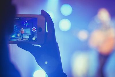 Cropped hand of person photographing guitarist during concert