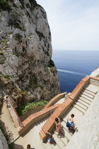 High angle view of people on rock by sea against sky