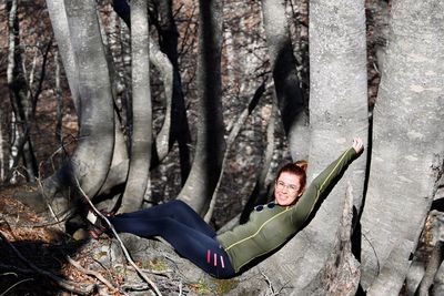 Portrait of young woman sitting on tree trunk in forest