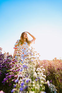 Beautiful pretty woman in a margaret aster flowers fields raise her hand to cover the sunlight