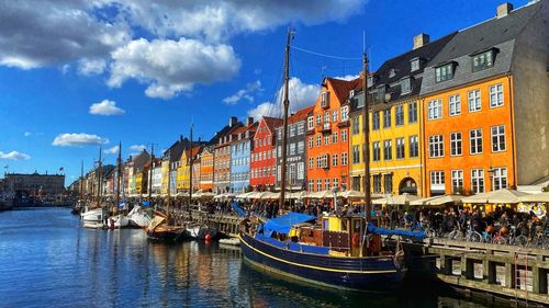 Boats in river in city against sky