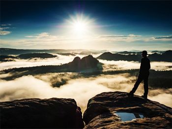 Man standing on rocks against sky