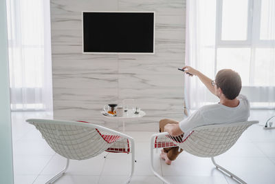 Leisure time. man sitting in a chair watching tv holding remote control