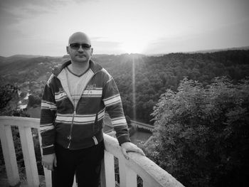 Portrait of young man standing on mountain against sky