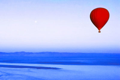 Hot air balloon flying over sea against sky