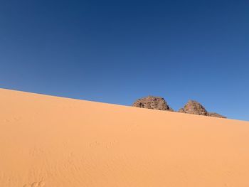 Sand dunes in desert against clear blue sky