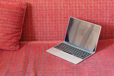 Close-up of laptop on table against wall