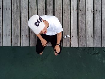 Directly above view of man sitting on jetty in sea